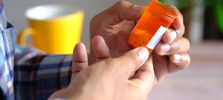 Rear view young man hand hold medical pill container