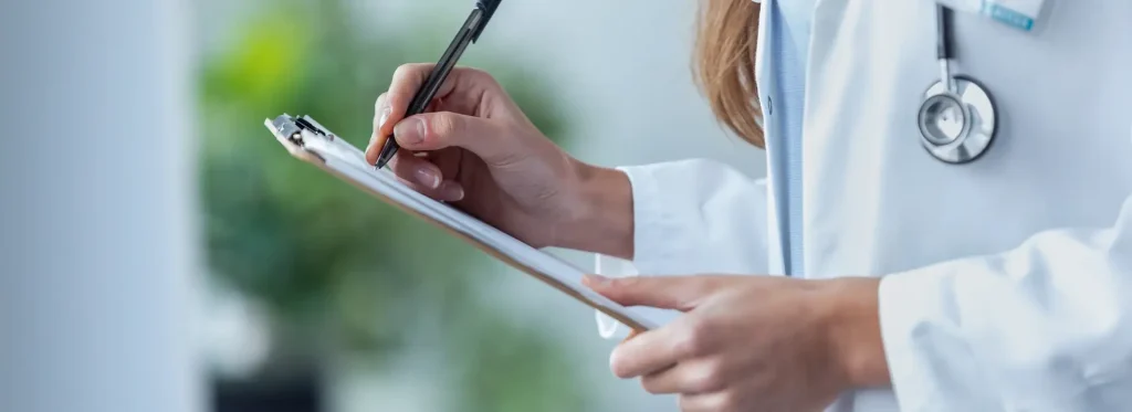 Physician writing about alcohol addiction on clipboard.