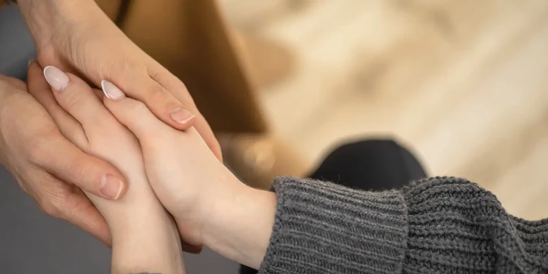 liberty therapy woman holding hands while sitting couch
