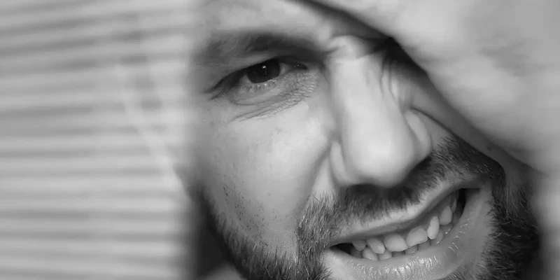 Man holding his head in discomfort after heavy drinking, illustrating the difference between a hangover and alcohol poisoning symptoms.