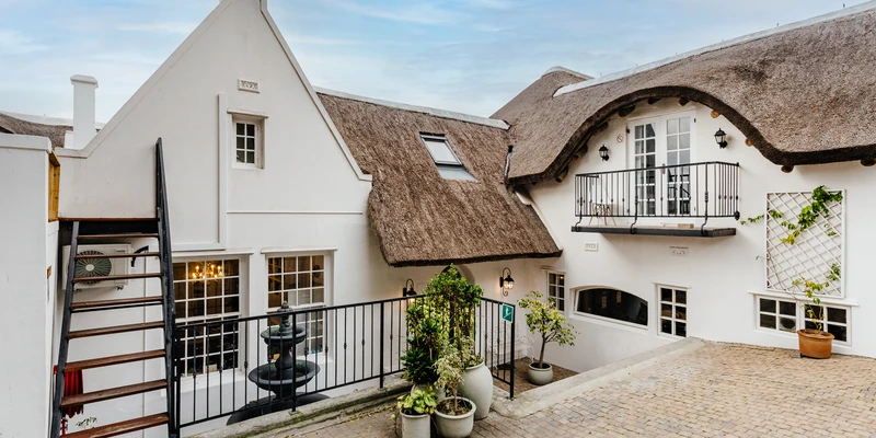 Exterior view of a peaceful residential recovery home with thatched roof, representing a safe environment for alcohol detox and rehabilitation.