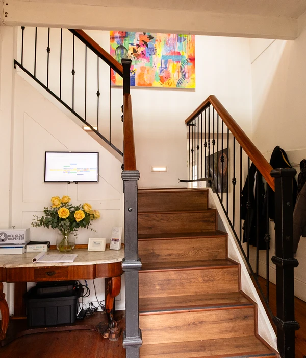 Wooden staircase with a marble table, yellow roses, and colorful abstract art on the wall in a bright indoor setting.