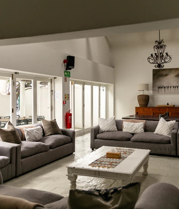 Large common room with gray sofas, a white coffee table, and tall glass doors leading to a bright outdoor patio.
